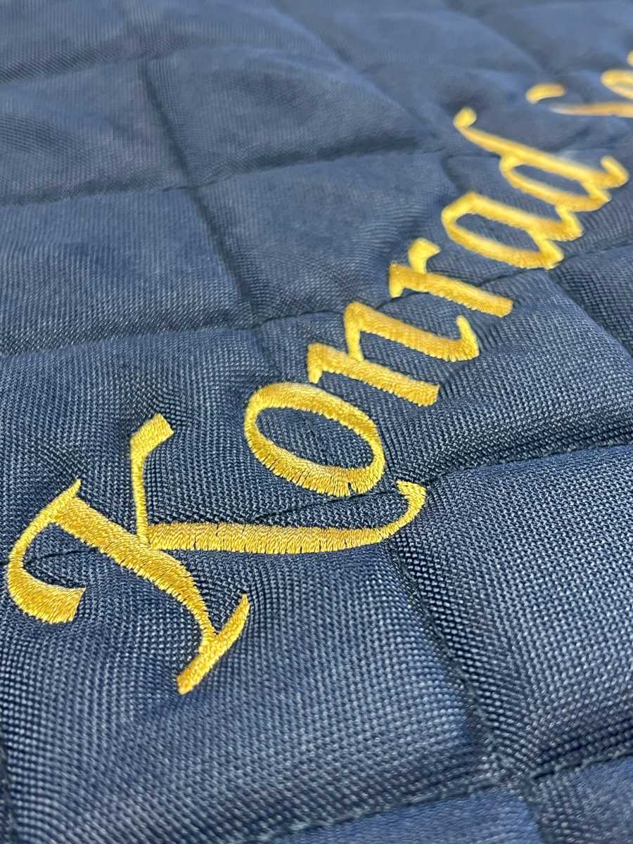 Individuelle Schriftstickerei in Gold auf blauer Schabracke